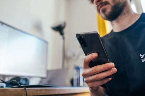 man with beard holding black smartphone