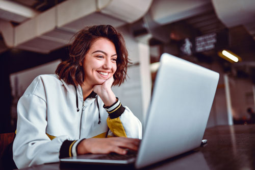 woman smiling as she looks at her laptop